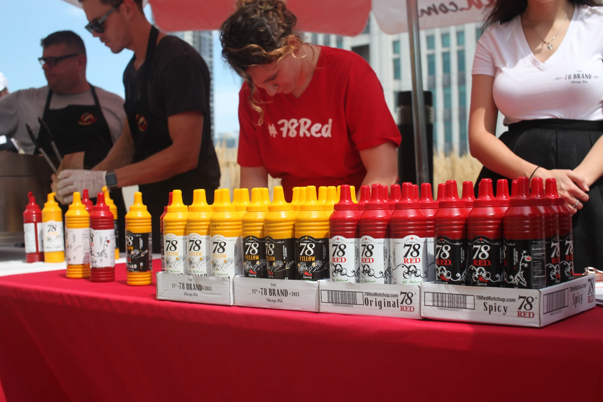 78 Brand team running a sampling event with rows of red ketchup and yellow mustard bottles at an outdoor foodservice activation in Chicago.